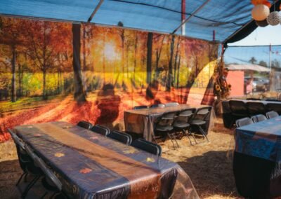 Party tent tables in front of an autumn forest backdrop